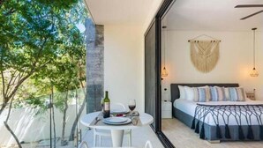 Une chambre moderne avec un lit, une table de chevet et une vue sur un balcon équipé d’une table et de chaises.