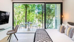 Une chambre moderne avec une grande fenêtre, un lit, une télévision et une petite table avec des chaises.
