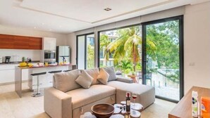 Ein modernes Wohnzimmer mit einer Couch, einem Couchtisch und Blick auf einen Balkon mit Palmen.
