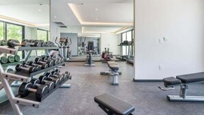 Een moderne sportschool met diverse trainingsapparaten, waaronder gewichten, banken en cardio-apparatuur.