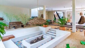 A modern interior with a central seating area, a staircase, and potted plants.