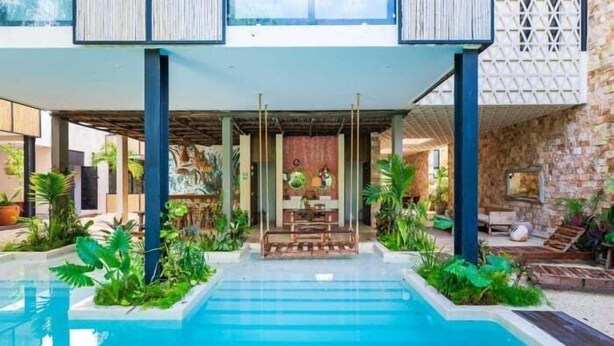 A pool area with a clear view of the pool, surrounded by lush greenery and a wooden deck.