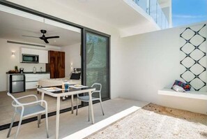 Eine moderne Küche mit Mikrowelle und Schränken, ein Essbereich mit Tisch und Stühlen sowie eine große Schiebeglastür, die auf eine Terrasse im Freien führt.