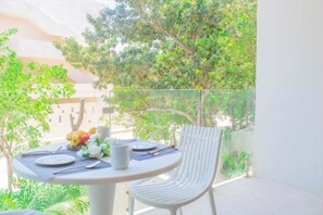 A round table with a white chair, a vase with flowers, and a plate set on a balcony with a glass railing. - A215 CPL, Fabulous air conditioned studio-2 (Tulum)