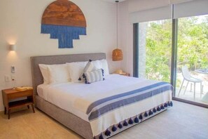 A bedroom with a large bed, a nightstand, a wall-mounted artwork, and a view of the outdoors. - A215 CPL, Fabulous air conditioned studio-2 (Tulum)