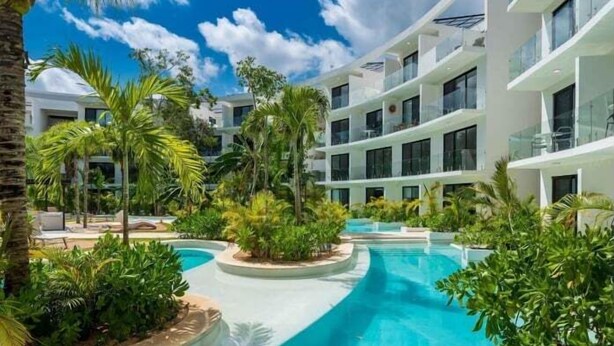 A modern hotel with a central swimming pool surrounded by lush greenery and palm trees. - A201 CPL, Spectacular Studio Jungle View-2 (Tulum)