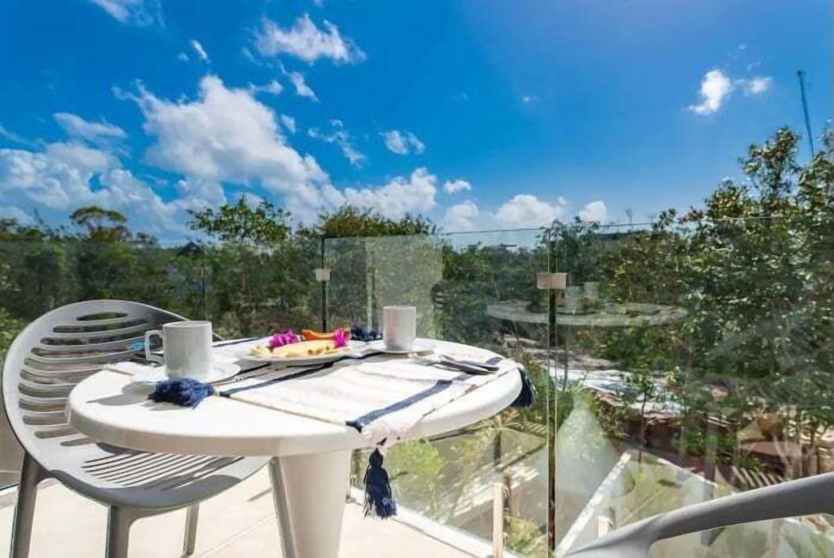 A balcony with a round table, chairs, and a view of a cityscape.