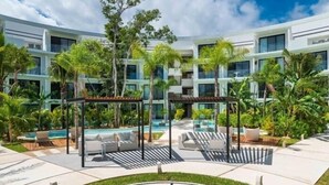 A modern hotel with a pool area, outdoor seating, and lush greenery. - A207 CPL, Magnificent air conditioned studio-2 (Tulum)