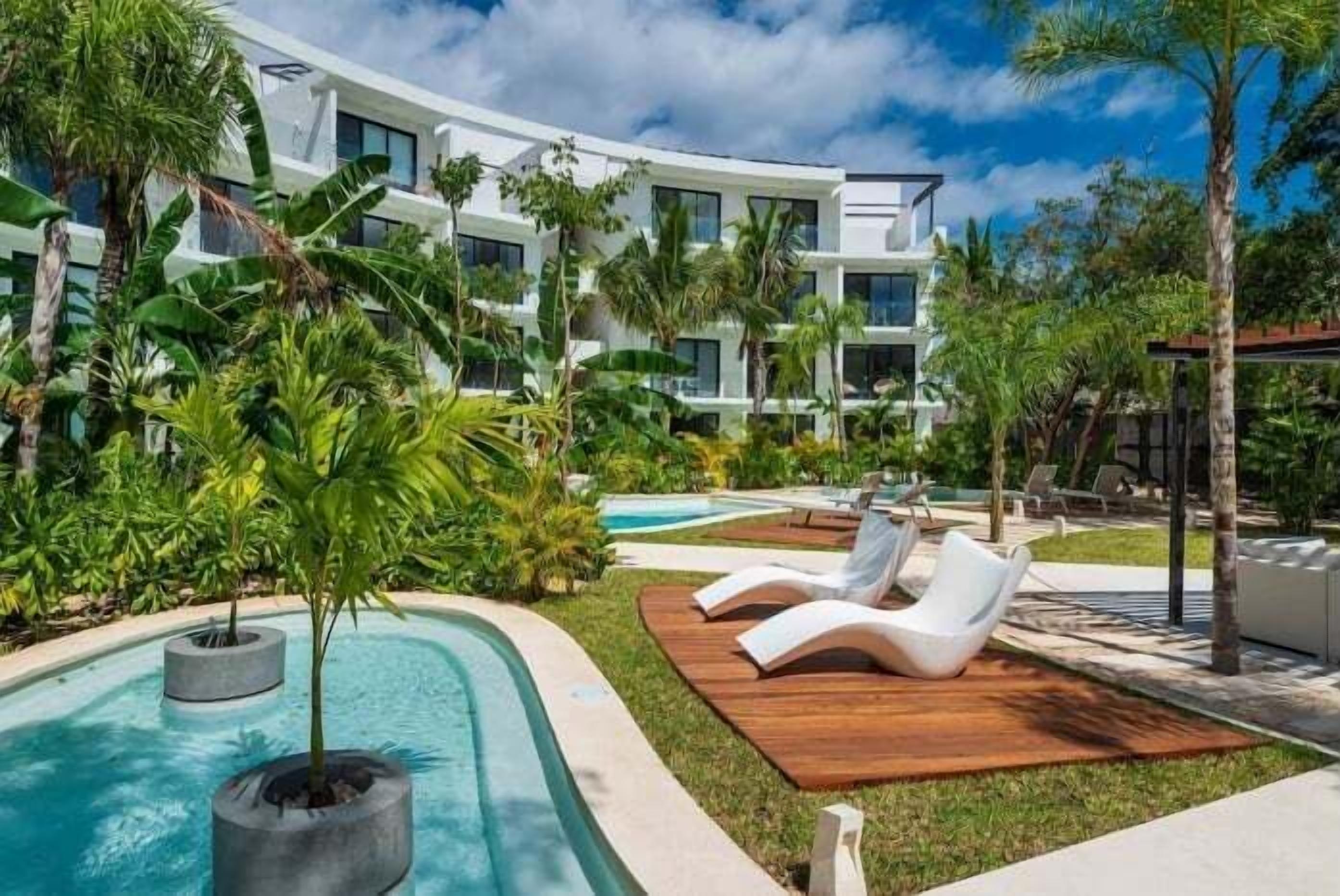 A resort with a pool, lounge chairs, and lush greenery.