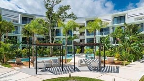 Ein modernes Hotel mit Poolbereich, Außenbestuhlung und üppiger Bepflanzung.