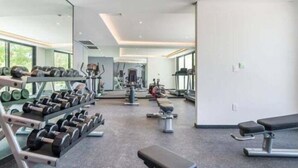 Un gimnasio moderno con equipamiento de levantamiento de pesas, máquinas de cardio y bancos.