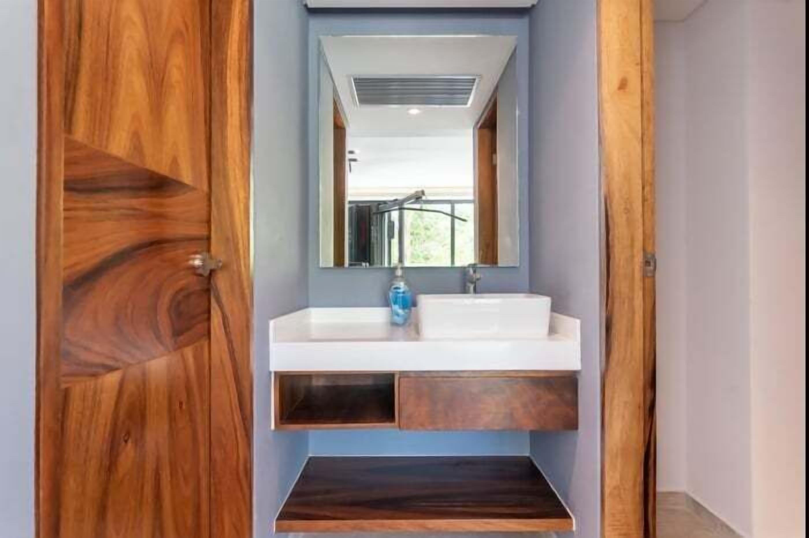 A bathroom with a wooden vanity, a white sink, and a mirror above it.