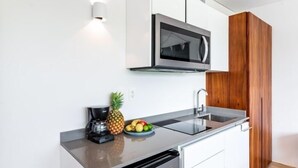 Una cucina moderna con forno a microonde integrato, macchina del caffè e una ciotola di frutta sul piano di lavoro.