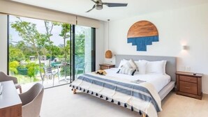 A bedroom with a bed, a ceiling fan, a nightstand, and a view of the outdoors. - B310 CPL, Interesting studio with lagoon view-2 (Tulum)