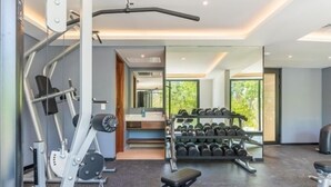 A modern gym with exercise equipment, a bench, and a rack of dumbbells. - B409 CPL, Studio Jungle View-No Air Conditioning-2 (Tulum)