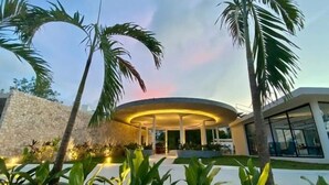 A modern building with a circular central structure, surrounded by a stone wall and palm trees. - C306 CPL, Radiante Studio Lagoon View-2 (Tulum)