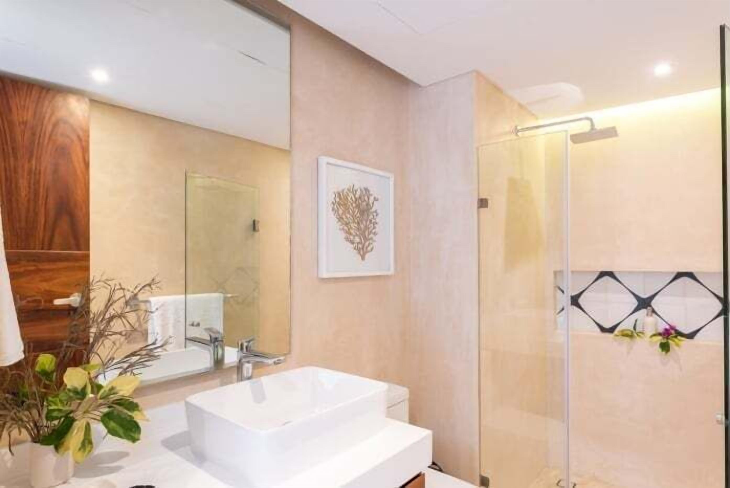 Ein modernes Badezimmer mit einem großen weißen Waschbecken, einer Duschkabine aus Glas und einer Wand mit Holzverkleidung.