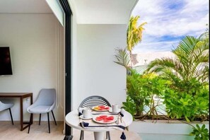 Ein Balkon mit Tisch für zwei Personen, einem Stuhl und einem Fernseher an der Wand.