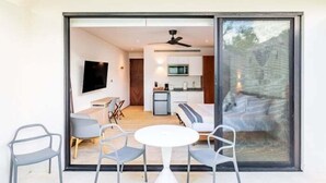 Un interno moderno con zona pranzo, cucina e un'ampia porta scorrevole in vetro che si apre su uno spazio esterno.