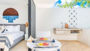 Ein modernes Schlafzimmer mit einem Bett, einem Esstisch mit einer Mahlzeit und einer außergewöhnlichen Deckenmalerei.