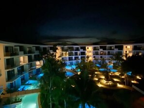 A multi-story hotel with a pool area at night. - E203 CPL, Cowork /Gym/Estilo moderno / Jardín-2 (Tulum)