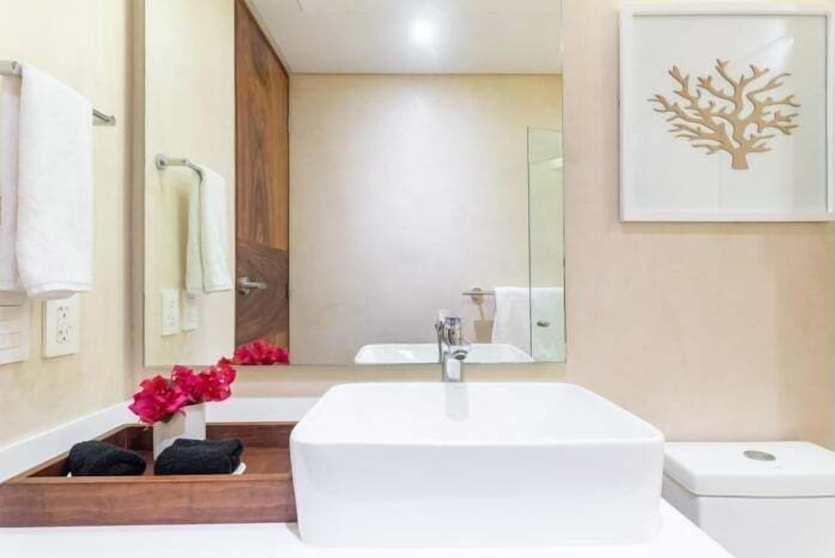 A modern bathroom with a large white sink, a mirror, and a wooden vanity.