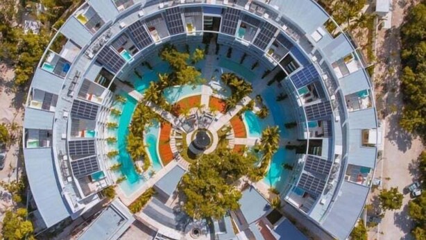 Ein kreisförmiges Hotel mit einem zentralen Pool, umgeben von mehreren Stockwerken mit Balkonen.
