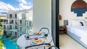 Ein modernes Hotelzimmer mit Balkon und Blick auf einen Pool sowie andere Gebäude.