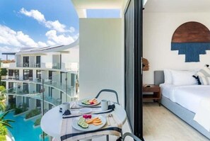 A modern hotel room with a balcony overlooking a pool and other buildings. - BPH04 CPL, Luxury estudio PH con piscina privada-2 (Tulum)