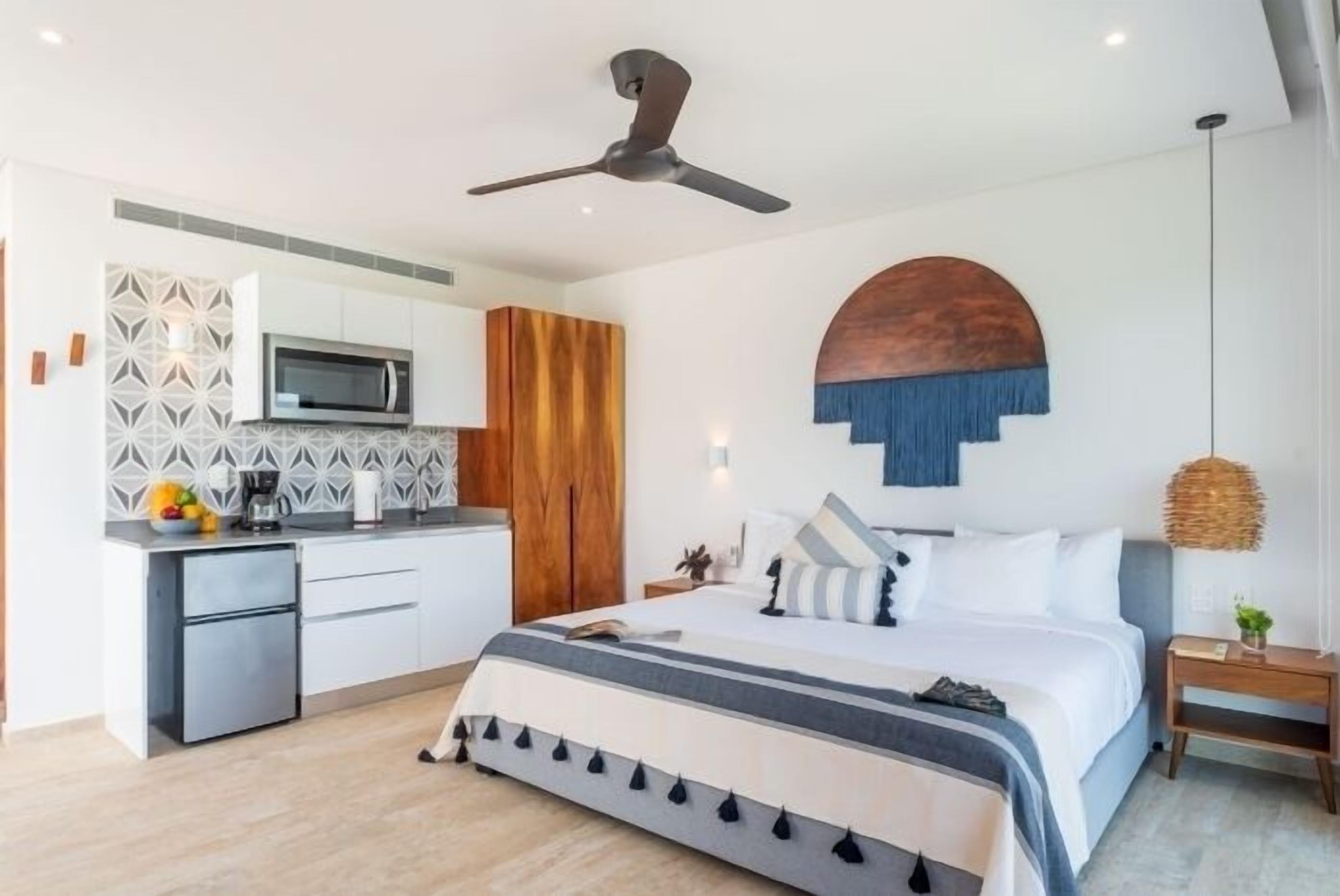 Une chambre à coucher moderne, avec un lit, une table de chevet et un ventilateur de plafond.