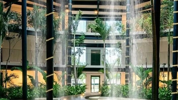 Un atrium à plusieurs niveaux agrémenté d’éléments d’eau, de verdure et d’une allée centrale.