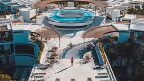 Un área de piscina en la azotea con una piscina circular, sillones de sol y una zona de estar cubierta.
