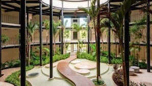 A circular atrium with a central pathway, surrounded by greenery and palm trees. - 105D PANOR, Large Studio with 360° Pool-2 (Tulum)