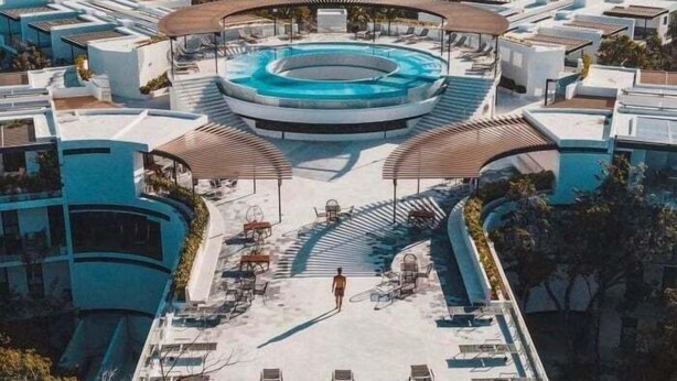Un espace piscine aménagé sur le toit, comprenant une piscine circulaire, des chaises longues et un espace salon couvert.