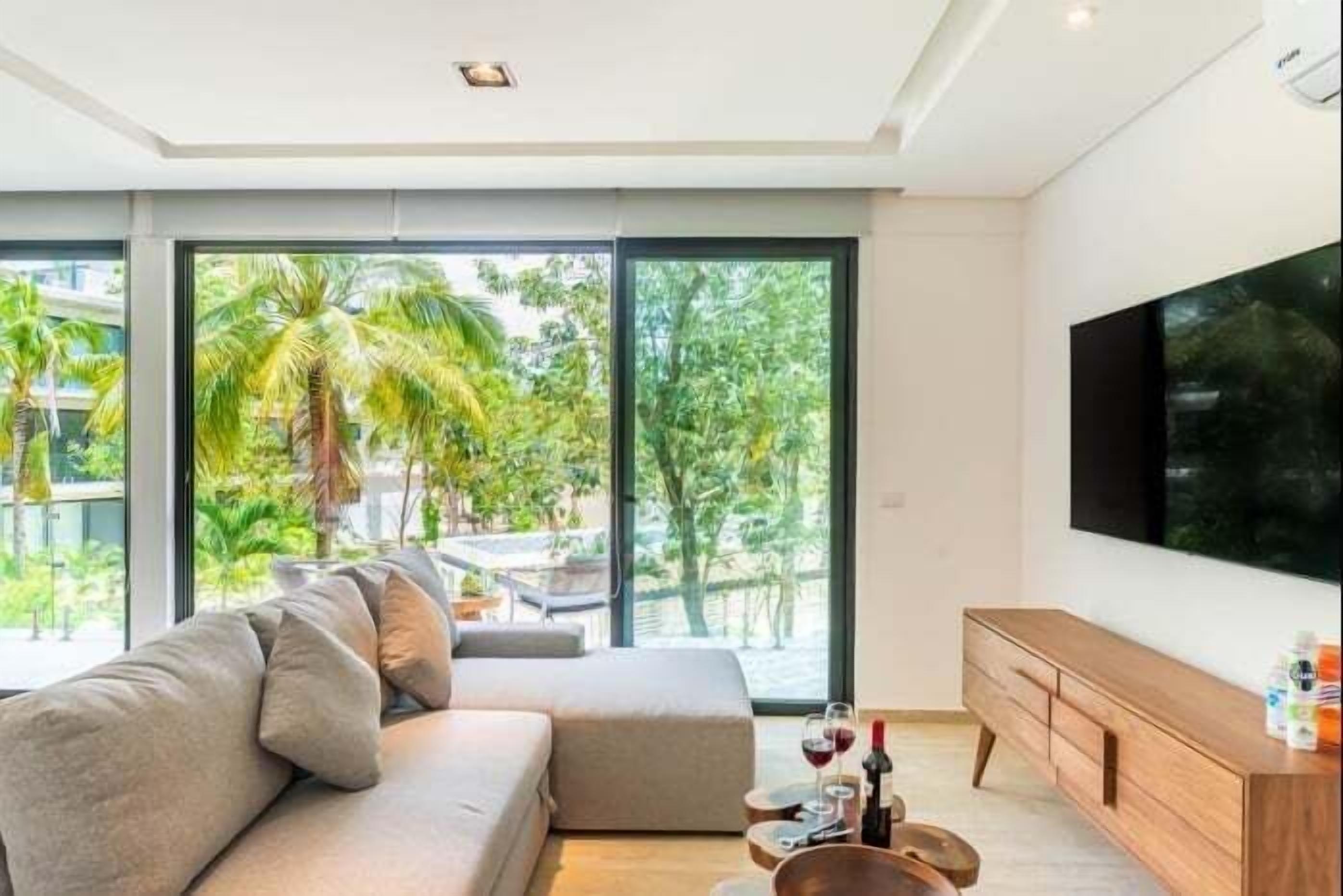 A modern living room with a large sofa, a wooden cabinet, and a flat-screen TV.