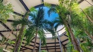 A circular atrium with a high ceiling, surrounded by tall palm trees and lush greenery. - PH8C PANOR, Luxury Penthouse Alberca Privada-2 (Tulum)