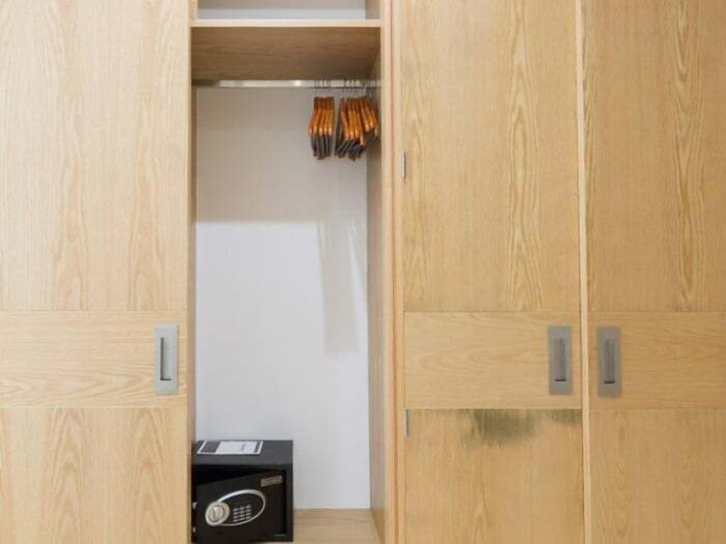 A wooden wardrobe with a handle and a small black box on the bottom shelf.