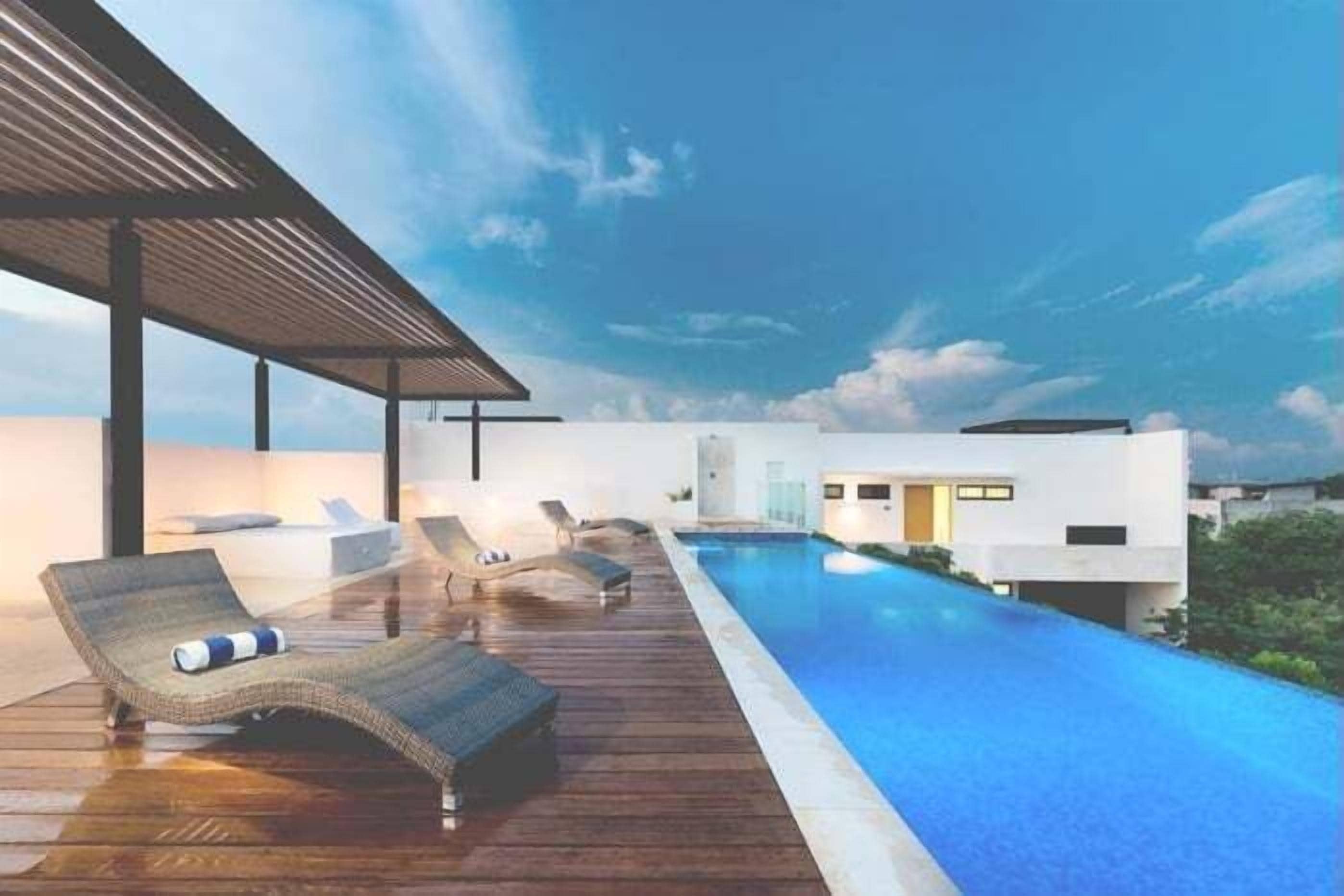 A modern pool area with lounge chairs and a covered seating area.