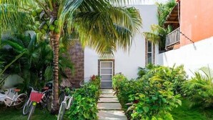 A pathway leading to a building with a door, surrounded by lush greenery and bicycles parked on the left. - Casa Alegria, New Villa Private Pool!-2 (Tulum)