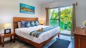 A hotel room with a large bed, a ceiling fan, a painting on the wall, and a view of greenery through the window. - Casa Alegria, New Villa Private Pool!-2 (Tulum)