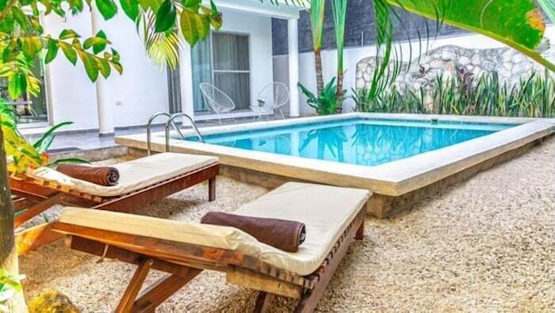 A pool area with lounge chairs and a stone wall. - Casa Alegria, New Villa Private Pool!-2 (Tulum)