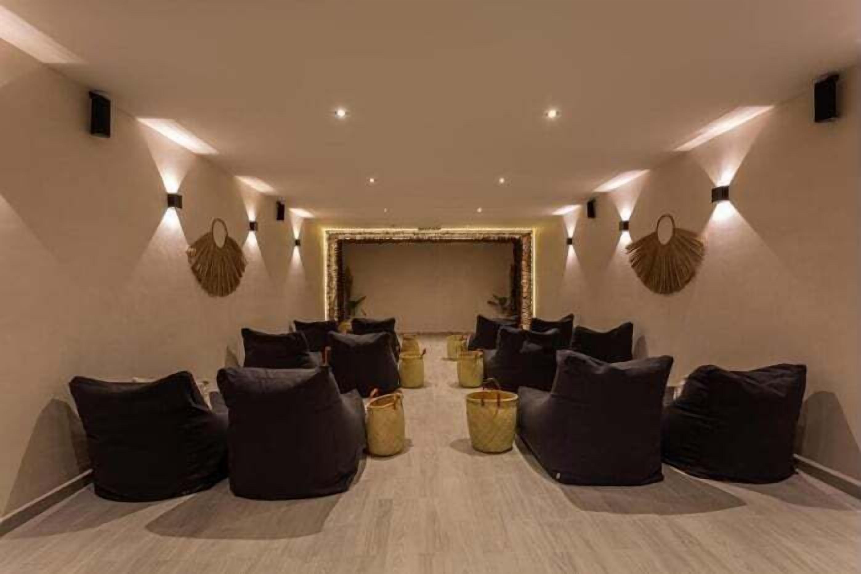 A spa room with black bean bags, a central light fixture, and wall-mounted fans.