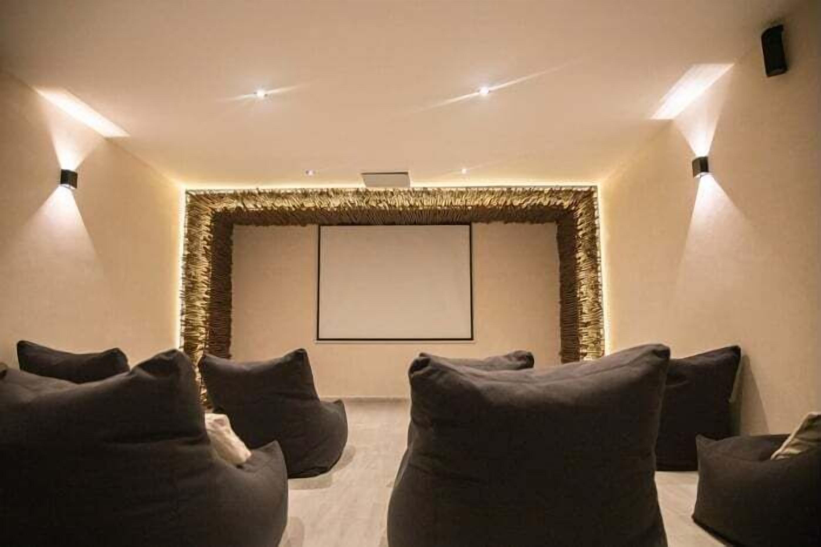 A home theater room with a large screen, comfortable seating, and ambient lighting.