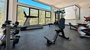 Ein modernes Fitnessstudio mit Laufband, Kraftgeräten und Bänken.