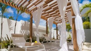 Een overdekt terras met witte stoelen en een houten pergola.