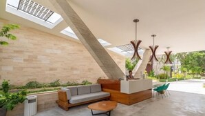 Een moderne lobby met een hoge plafond, een receptiebalie, zithoek en uitzicht op de omgeving.