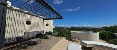 Una terraza en la azotea con piso de madera, mobiliario exterior y una piscina.