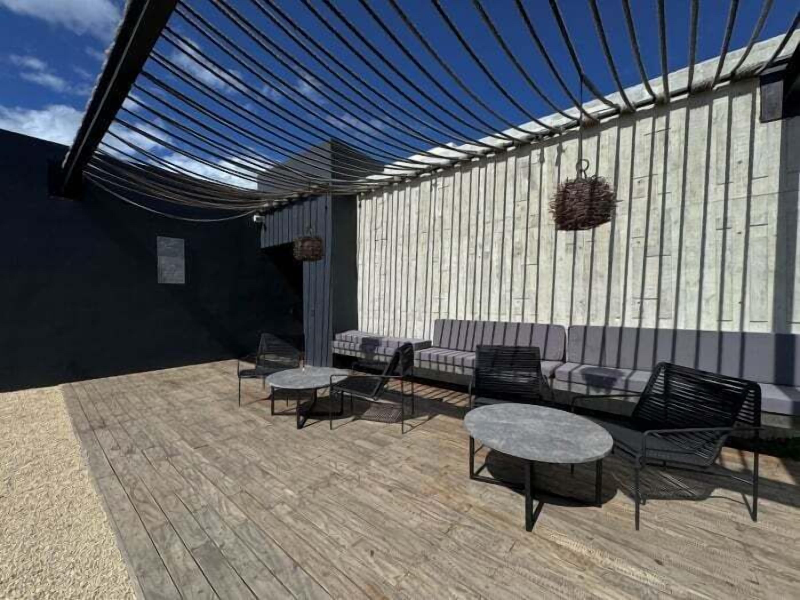 Une terrasse extérieure dotée d’une plateforme en bois, d’un espace salon confortable et d’une pergola au-dessus.