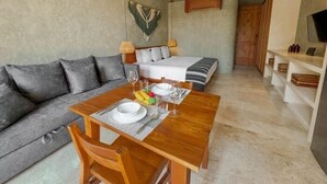 A compact hotel room with a sofa, a bed, a dining table with chairs, a ceiling fan, and a TV on the wall. - SEREMONIA 206, Tu Refugio Ideal-2 (Tulum)