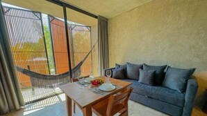 A room with a dining table set for two, a sofa, and a hammock. - SEREMONIA 206, Tu Refugio Ideal-2 (Tulum)